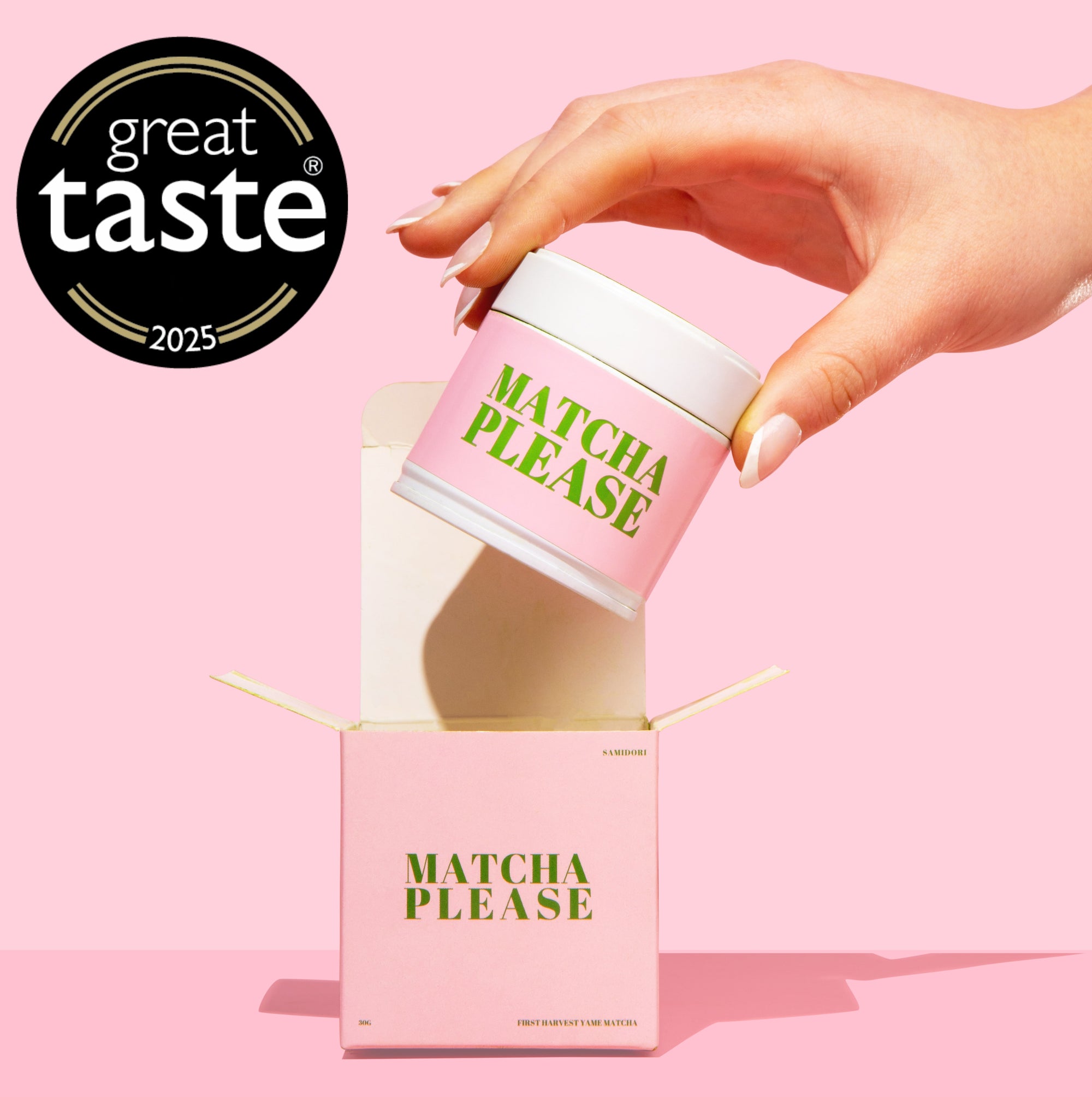 Hand holding a pink matcha container with 'Matcha Please' text, against a pink background with Great Taste logo.